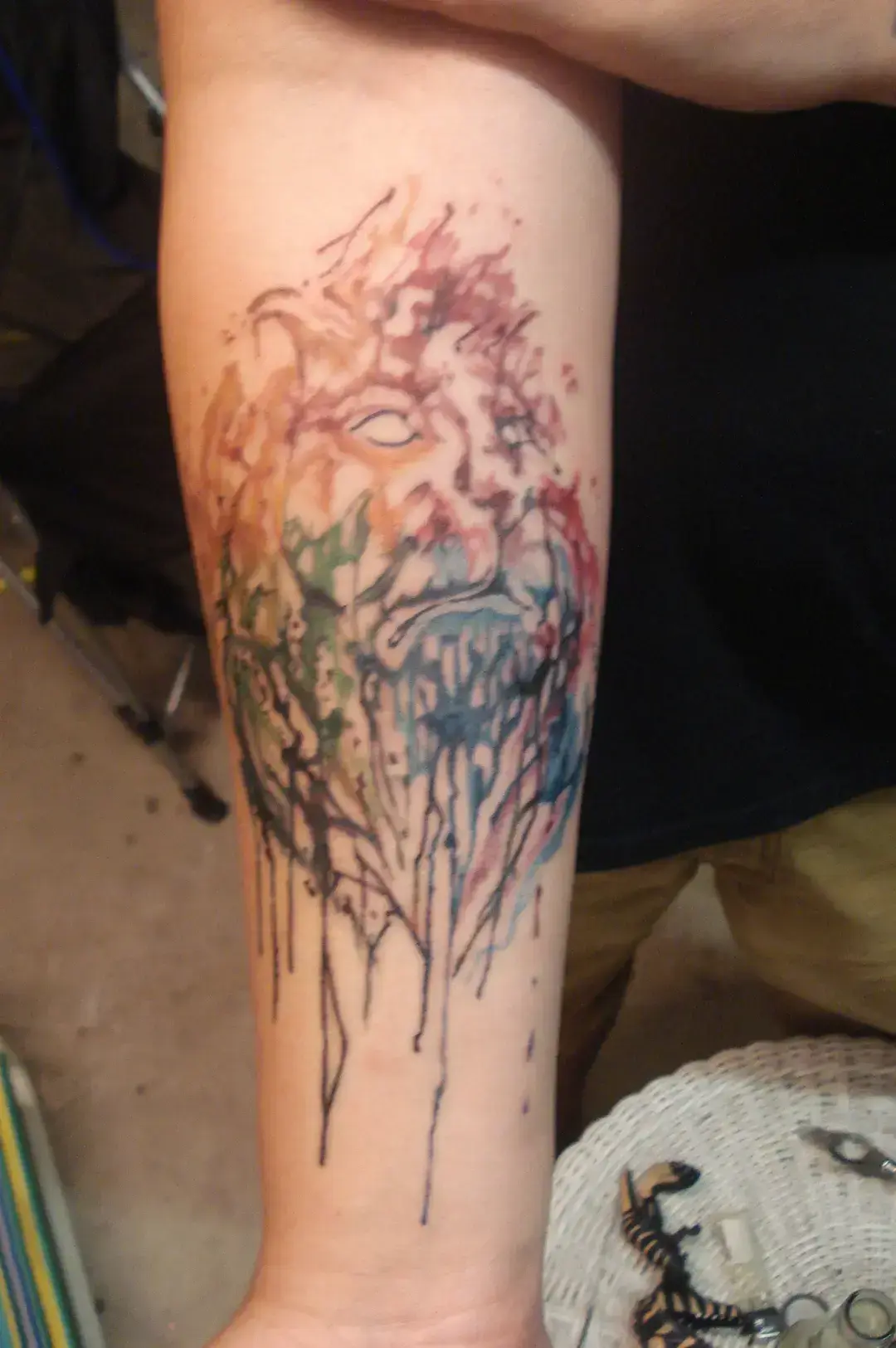 watercolor-lion-tattoo-bold-full-color-forearm-design-in-red-blue-green-yellow