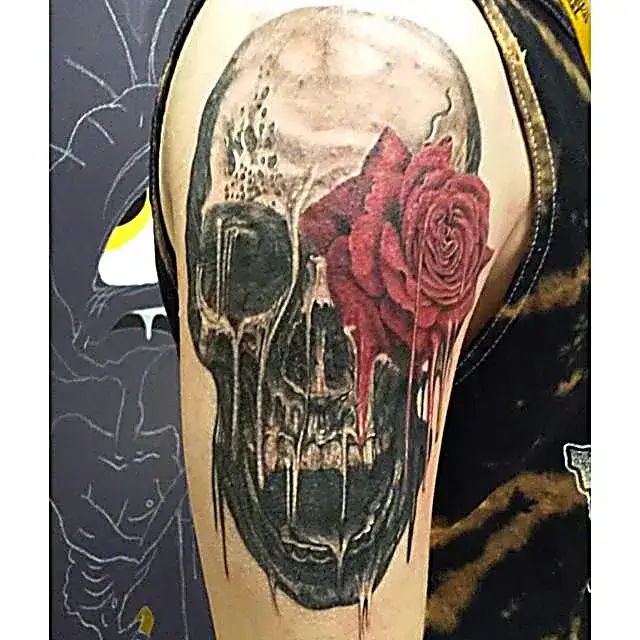 Life and death collide: Skull and rose tattoo on upper right arm with bold red detail.